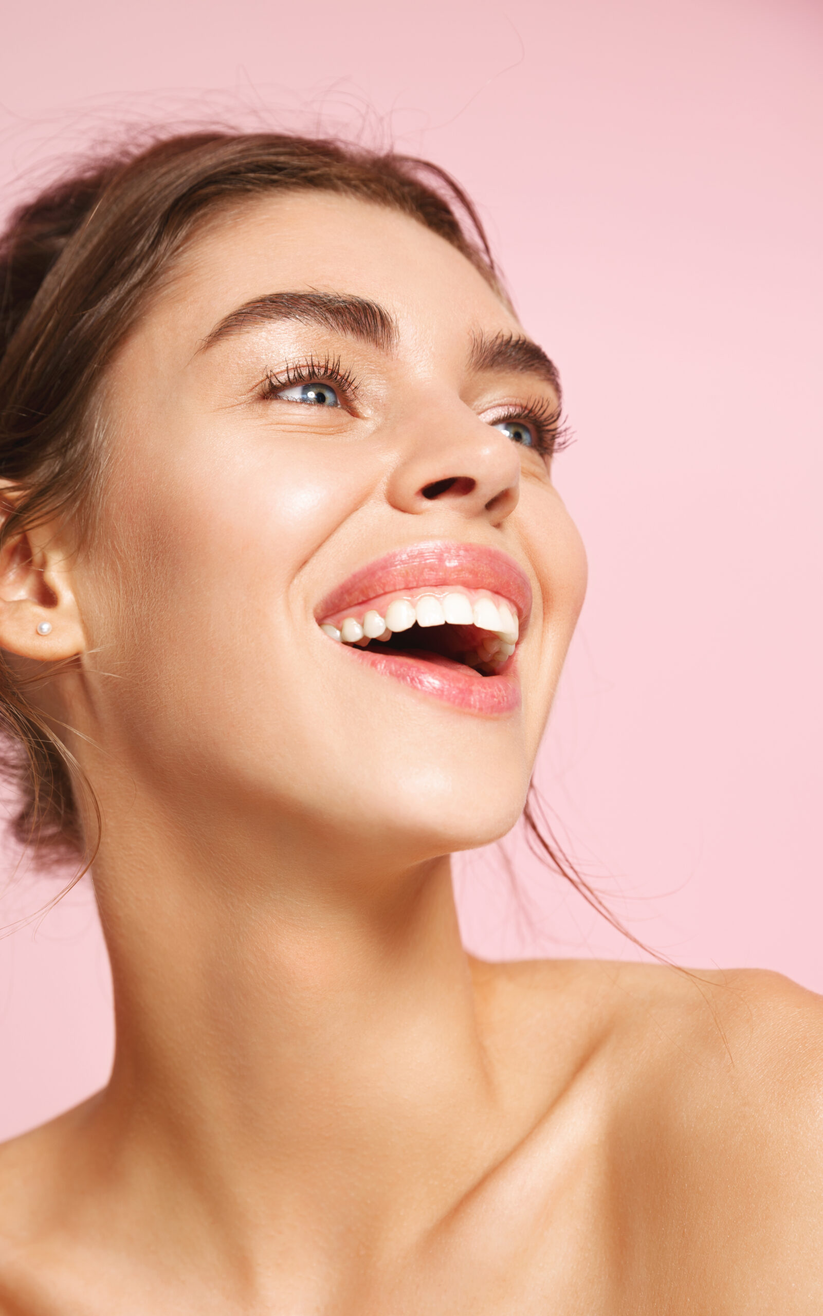 Beauty and makeup. Close up of happy girl smiling white teeth, standing half-naked on pink background and laughing. Young woman with glowing healthy skin, concept of skincare