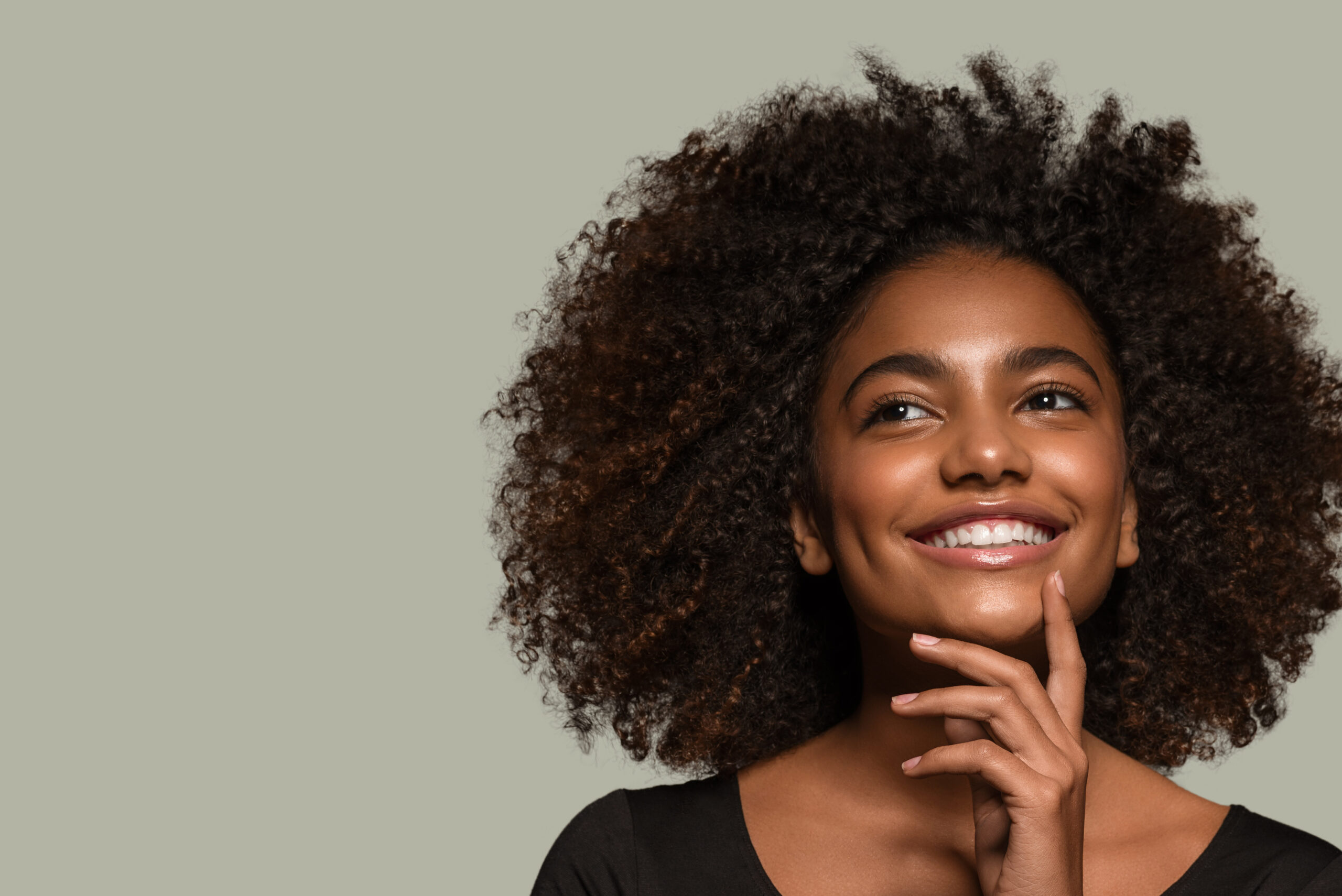 Beautiful african woman black t-shirt portrait afro haircut touching her face Color background green