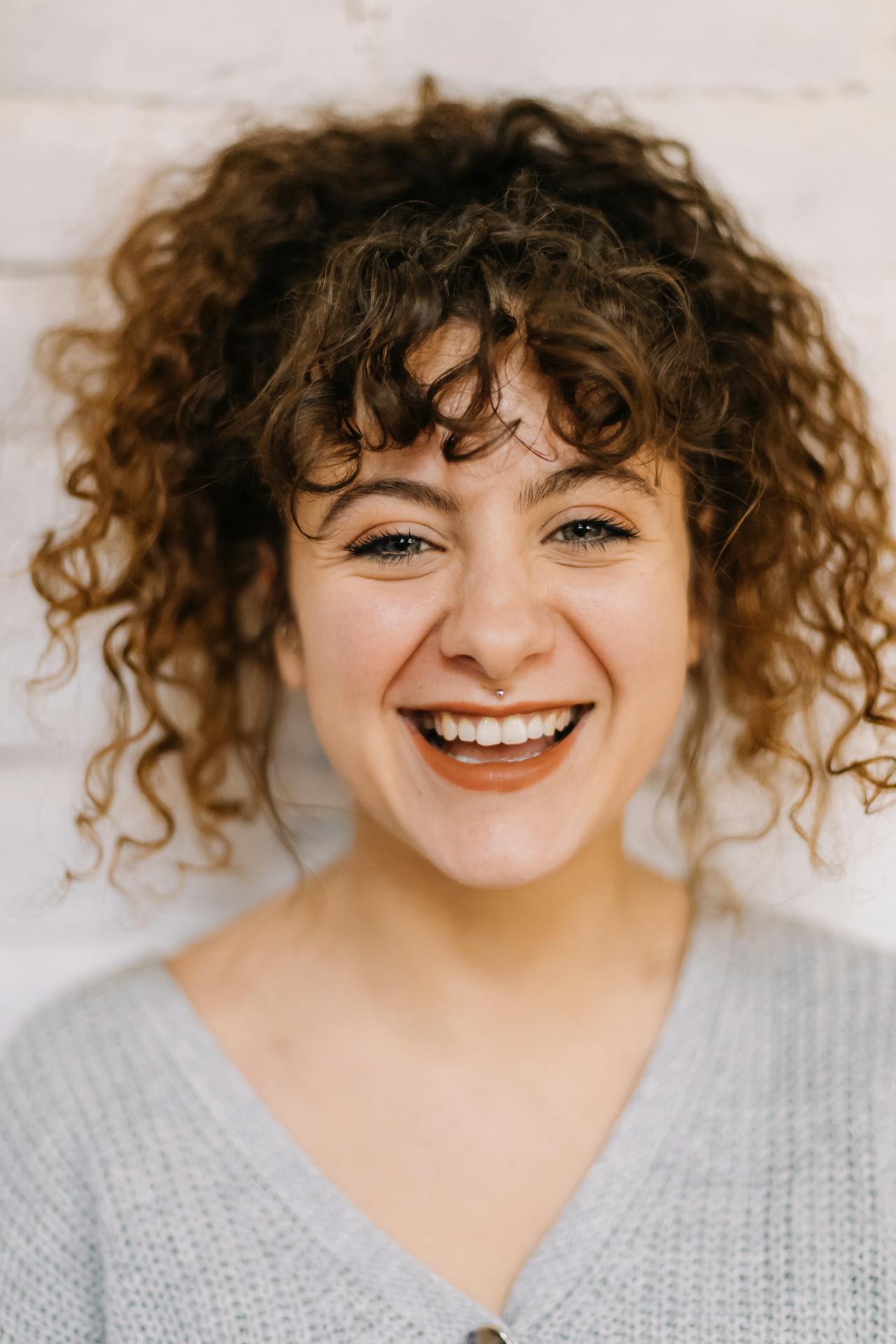 Close-Up Shot of a Curly-Haired Woman Looking at Camera
