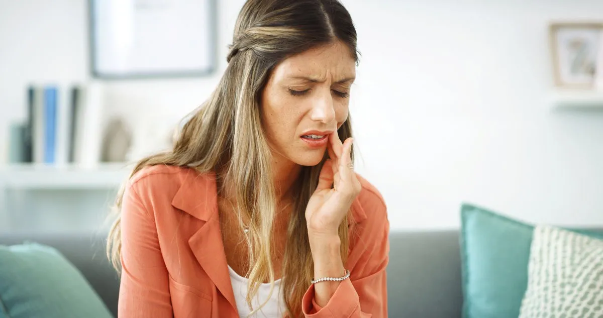 Woman, relax and pain from toothache at house with cavity, dental problem and gum infection. Female person, discomfort and touch cheek for sore gingivitis